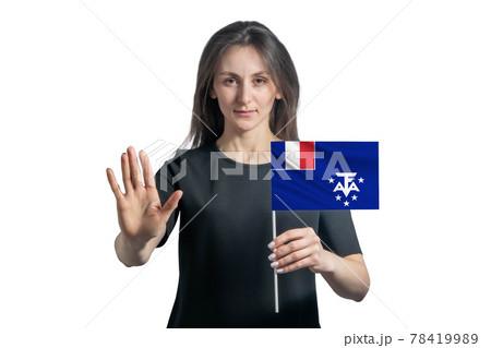 Happy young white woman holding flag of French Southern and Antarctic Territories and with a serious face shows a hand stop sign isolated on a white background Happy young white woman holding flag of French Southern and Antarctic Territories and with a serious face shows a hand stop sign isolated on a white background 78419989