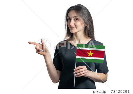Happy young white woman holding flag Suriname and points to the left isolated on a white background 78420291