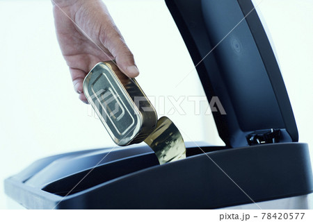 man throwing a tin can in a home recycling bin 78420577