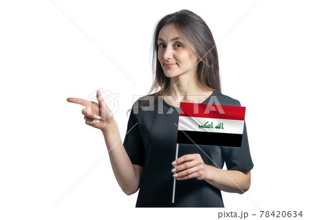 Happy young white woman holding flag Iraq and points to the left isolated on a white background Happy young white woman holding flag Iraq and points to the left isolated on a white background 78420634