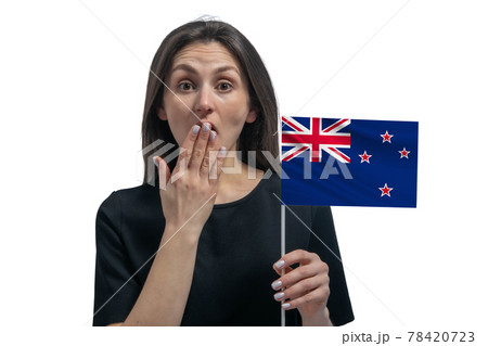 Happy young white woman holding flag of New Zealand and covers her mouth with her hand isolated on a white background 78420723