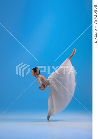 Young and incredibly beautiful ballerina is posing and dancing at blue studio full of light. 78420868