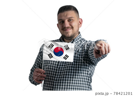 White guy holding a flag of South Korea and points forward in front of him isolated on a white background White guy holding a flag of South Korea and points forward in front of him isolated on a white background 78421201