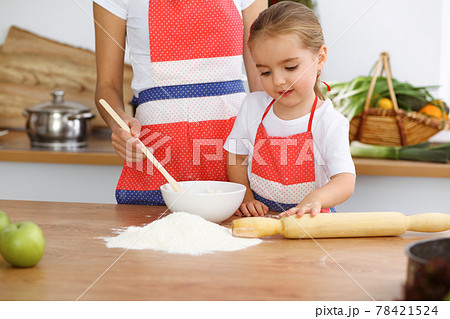 Happy woman and her daughter are kneading the dough and baking cookies for a delicious family feasting. Christmas, New year, Thanksgiving, Anniversary, Mothers Day. Healthy meal cooking concept Happy woman and her daughter are kneading the dough and baking cookies for a delicious family feasting. Christmas, New year, Thanksgiving, Anniversary, Mothers Day. Healthy meal cooking concept 78421524