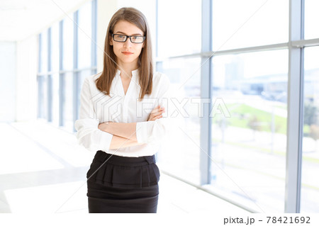 Beautiful female specialist with arms crossed standing in modern office and smiling charmingly. Working on design, data analysis, plan strategy. Business people concept Beautiful female specialist with arms crossed standing in modern office and smiling charmingly. Working on design, data analysis, plan strategy. Business people concept 78421692