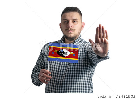 White guy holding a flag of Esvatini and with a serious face shows a hand stop sign isolated on a white background 78421903