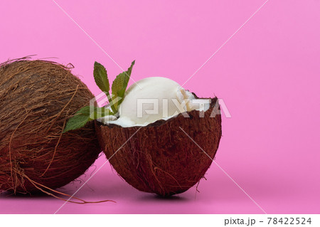 Vanilla ice cream balls in fresh coconut halves decorated with mint leaves on a pink background Vanilla ice cream balls in fresh coconut halves decorated with mint leaves on a pink background 78422524