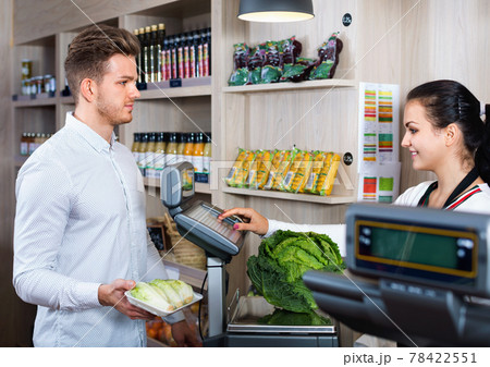 Shopping assistant helping customer to weigh cabbage 78422551