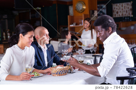 Group of people having dinner in cozy restaurant Group of people having dinner in cozy restaurant 78422628