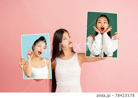 Young girl holding her portraits isolated over studio background with copyspace for ad. Concept of beauty, fashion. Young girl holding her portraits isolated over studio background with copyspace for ad. Concept of beauty, fashion. 78423578