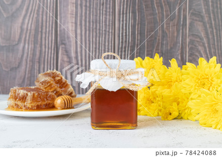 Fresh honey bottle with organic honeycomb and wild flower on wooden table. Healthy food concept. 78424088