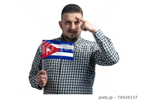 White guy holding a flag of Cuba and a finger touches the temple on the head isolated on a white background 78426337