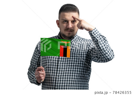 White guy holding a flag of Zambia and a finger touches the temple on the head isolated on a white background 78426355