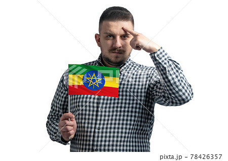 White guy holding a flag of Ethiopia and a finger touches the temple on the head isolated on a white background 78426357
