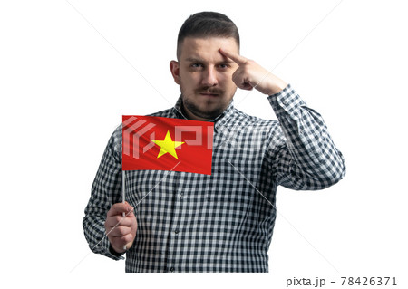 White guy holding a flag of Vietnam and a finger touches the temple on the head isolated on a white background White guy holding a flag of Vietnam and a finger touches the temple on the head isolated on a white background 78426371