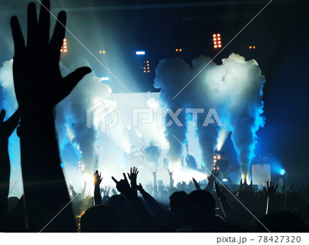 silhouettes of concert crowd in front of bright stage lights 78427320
