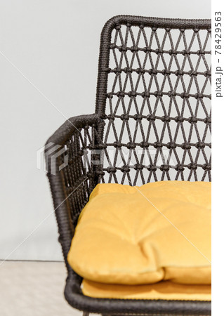 Black wicker chair with yellow pillows. Details 78429563
