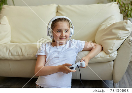 Pretty little girl in headphones are playing game console Pretty little girl in headphones are playing game console 78430698