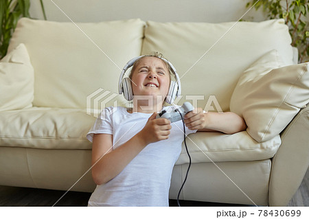 Pretty little girl in headphones are playing game console Pretty little girl in headphones are playing game console 78430699