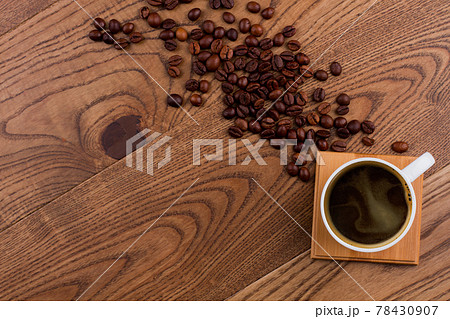 Topview cup of coffee and scattered coffee beans on wood. Topview cup of coffee and scattered coffee beans on wood. 78430907