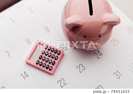 Pink piggy bank and calculator on a white calendar background, saving and investment concept. Top view Pink piggy bank and calculator on a white calendar background, saving and investment concept. Top view 78431635