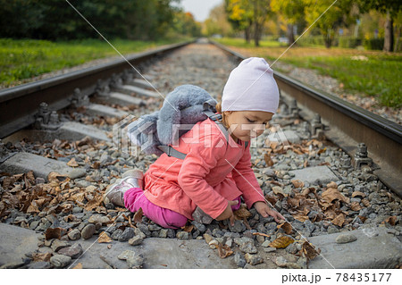 little girl sitting on the railroad tracks 78435177