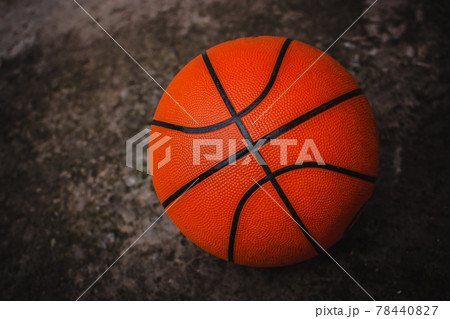 A dirty basketball on a concrete court after a street game. Dark background. A dirty basketball on a concrete court after a street game. Dark background. 78440827