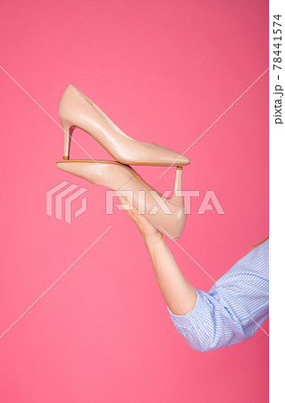 Women's shoes lie on a woman's hand. On a pink background Women's shoes lie on a woman's hand. On a pink background 78441574