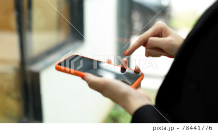 Businesswoman in black suit hand using smartphone in blurred background 78441776