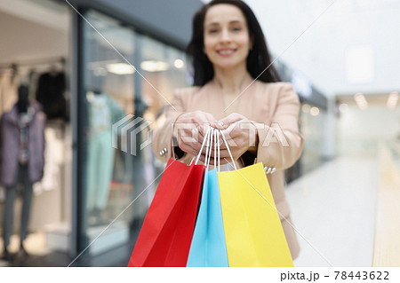 Woman holding in hands many multicolored paper bags with purchases in store closeup Woman holding in hands many multicolored paper bags with purchases in store closeup 78443622