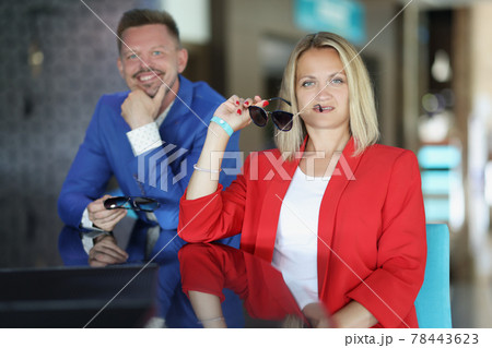 Young man and woman sit at bar with sunglasses in their hands Young man and woman sit at bar with sunglasses in their hands 78443623
