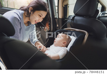 Asian young mother putting her baby son into car seat 78446151