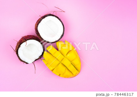 Two halves of a ripe coconut with a ripe mango half on a pink background. Two halves of a ripe coconut with a ripe mango half on a pink background. 78446317