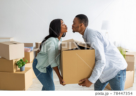 Home relocation concept. Loving african american couple carrying big carton box and trying to kiss 78447354