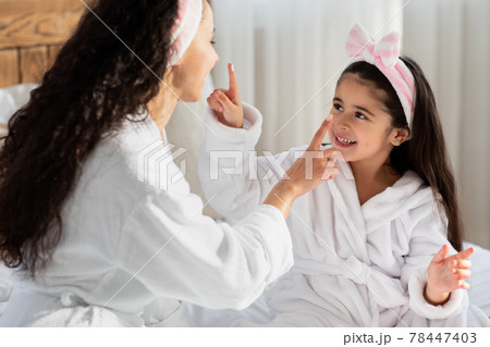 Closeup portrait of happy mother and daughter in bathrobes 78447403