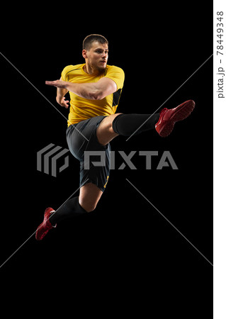 Powerful, flying above the field. Young football, soccer player in action, motion isolated on black background . 78449348