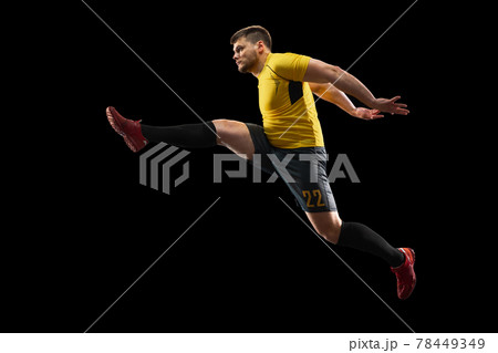 Powerful, flying above the field. Young football, soccer player in action, motion isolated on black background . 78449349