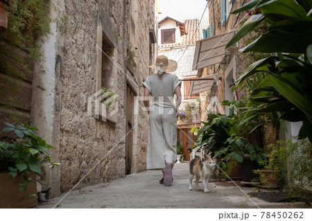 Rear view of beautiful blonde young female traveler wearing straw sun hat sightseeing and enjoying summer vacation in an old traditional costal town at Adriatic cost, Croatia Rear view of beautiful blonde young female traveler wearing straw sun hat sightseeing and enjoying summer vacation in an old traditional costal town at Adriatic cost, Croatia 78450262