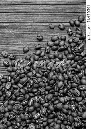 Scattered coffee beans on a wooden background. Black and white photo. Scattered coffee beans on a wooden background. Black and white photo. 78450591