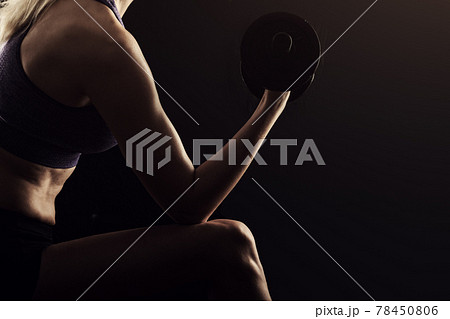 Slim athletic woman Holding dumbbell in the hand on black Slim athletic woman Holding dumbbell in the hand on black 78450806