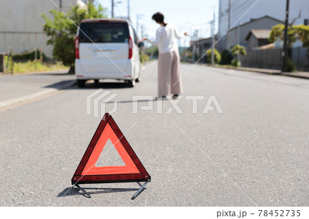 車が故障して三角停止表示版を置く女性 78452735