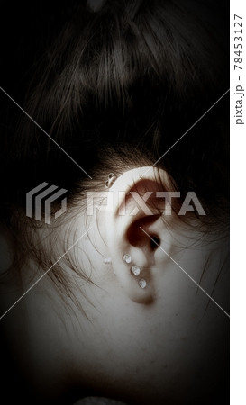 Black and white photo of an ear with earrings 78453127