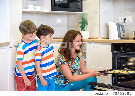 Kids and mother baking. Two children and parent cooking. Little boy and brother boy cook and bake in a white kitchen with modern oven. Sibling Brother making a cookies for dinner 78455299