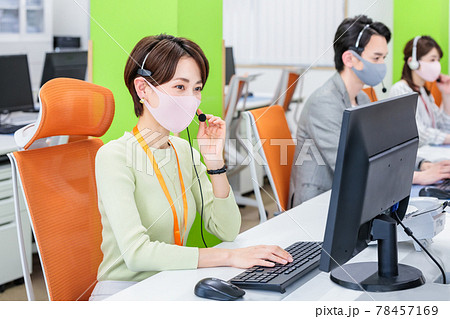 マスクとヘッドセットをつけて働くスタッフ 78457169