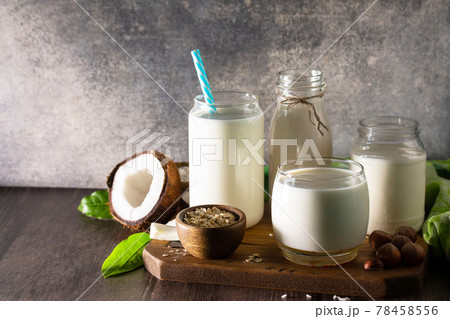Healthy vegan food concept. Assortment of organic vegan non dairy milk from coconut, nuts, oatmeal, rice on a kitchen table. Copy space. 78458556