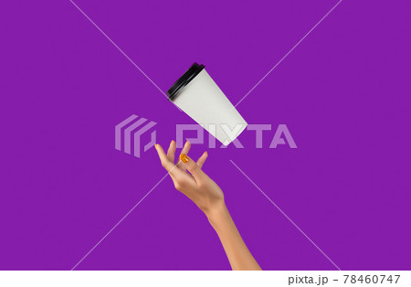 Womans hand with flying paper cup on purple background. Takeaway food and drink 78460747
