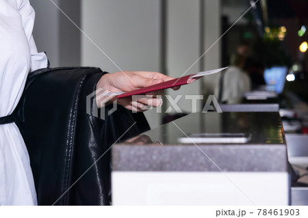 woman traveler's hand holding out passport and air ticket for passport control at the airport woman traveler's hand holding out passport and air ticket for passport control at the airport 78461903