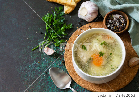Chicken soup with vegetables on a dark stone table top. Copy space. 78462053