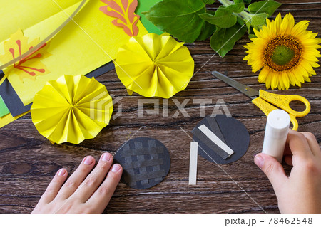 Instructions, step 7. Gift from a paper, sunflower flower on a wooden table. Childrens art project, handmade, crafts for children. Instructions, step 7. Gift from a paper, sunflower flower on a wooden table. Childrens art project, handmade, crafts for children. 78462548