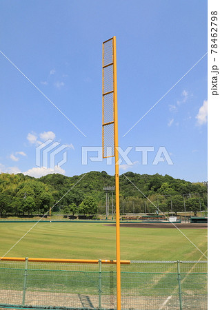 青空と山に映える野球場の黄色いファールポールの写真素材